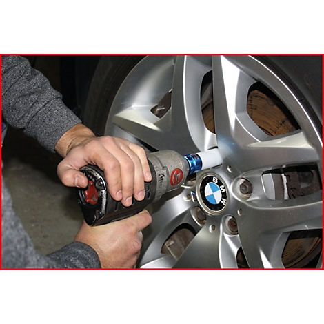 Jemand schraubt mit einem Schlagschrauber an einem Autoreifen. Das BMW-Logo ist sichtbar.